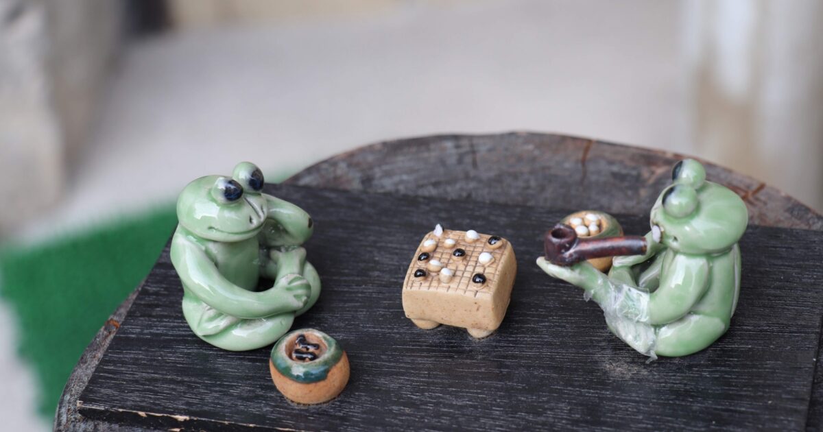 囲碁を楽しむカエルの陶器人形の置物