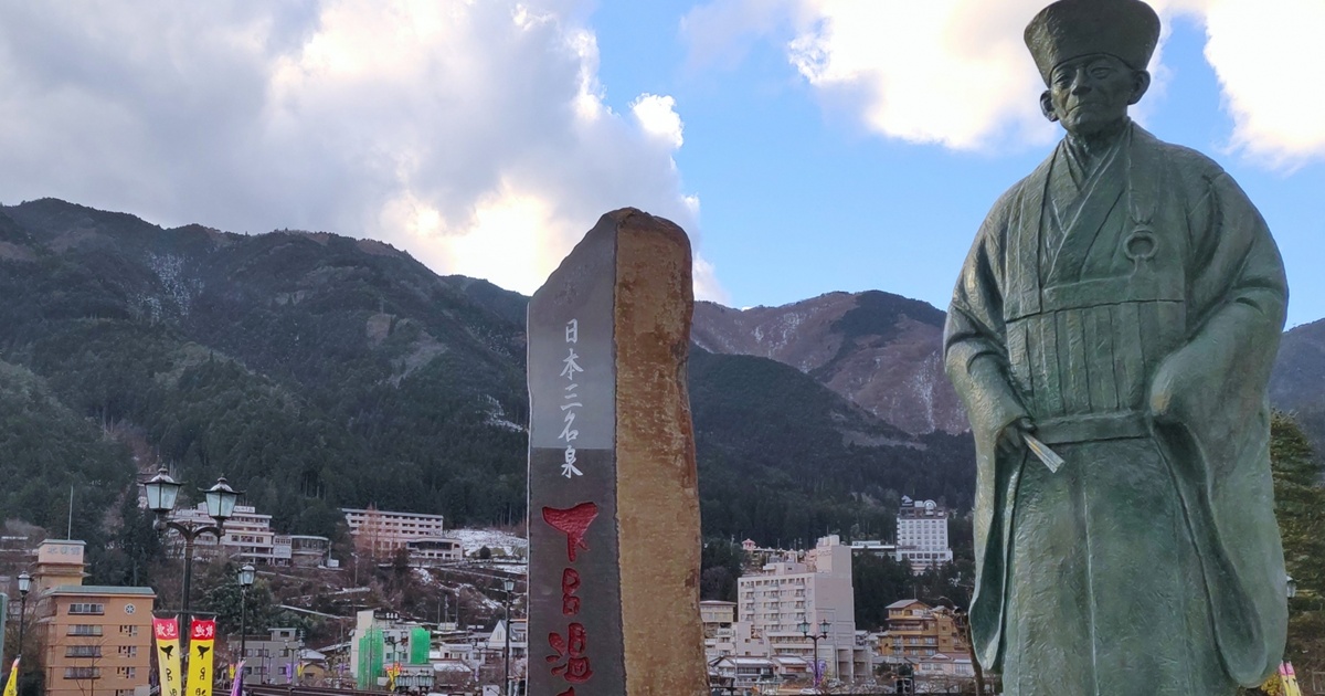 雪化粧した山と下呂温泉の石碑と銅像