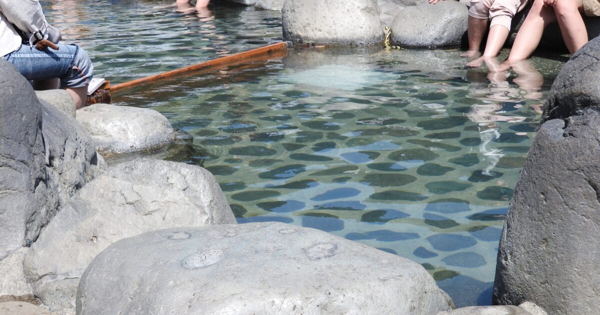 岩に囲まれた下呂温泉の足湯でくつろぐ人々