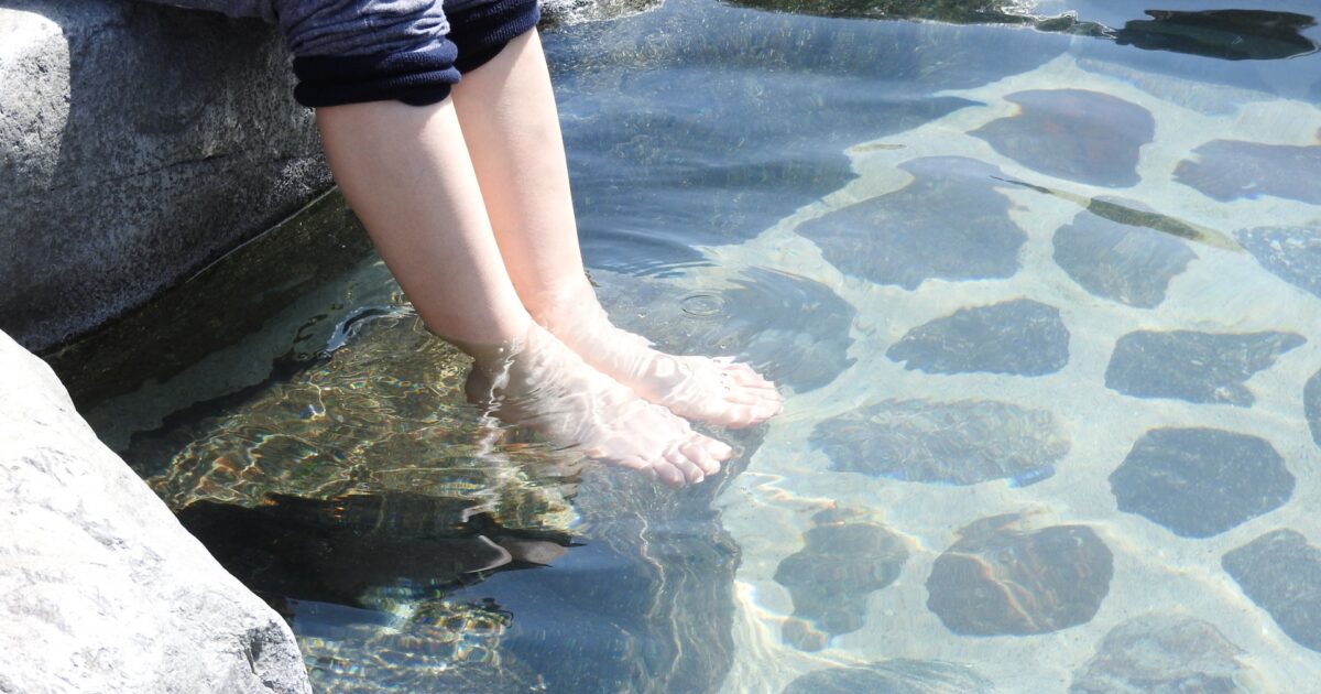 澄んだ湯に足を浸す下呂温泉の足湯体験