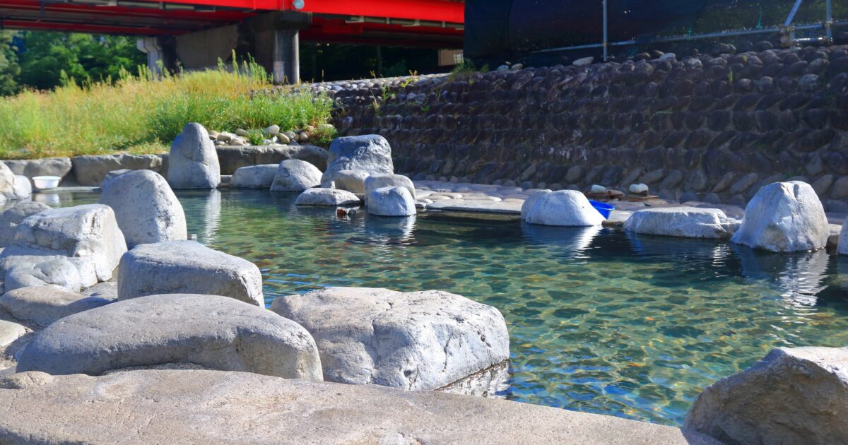 赤い橋のそばにある飛騨川沿いの下呂温泉露天風呂