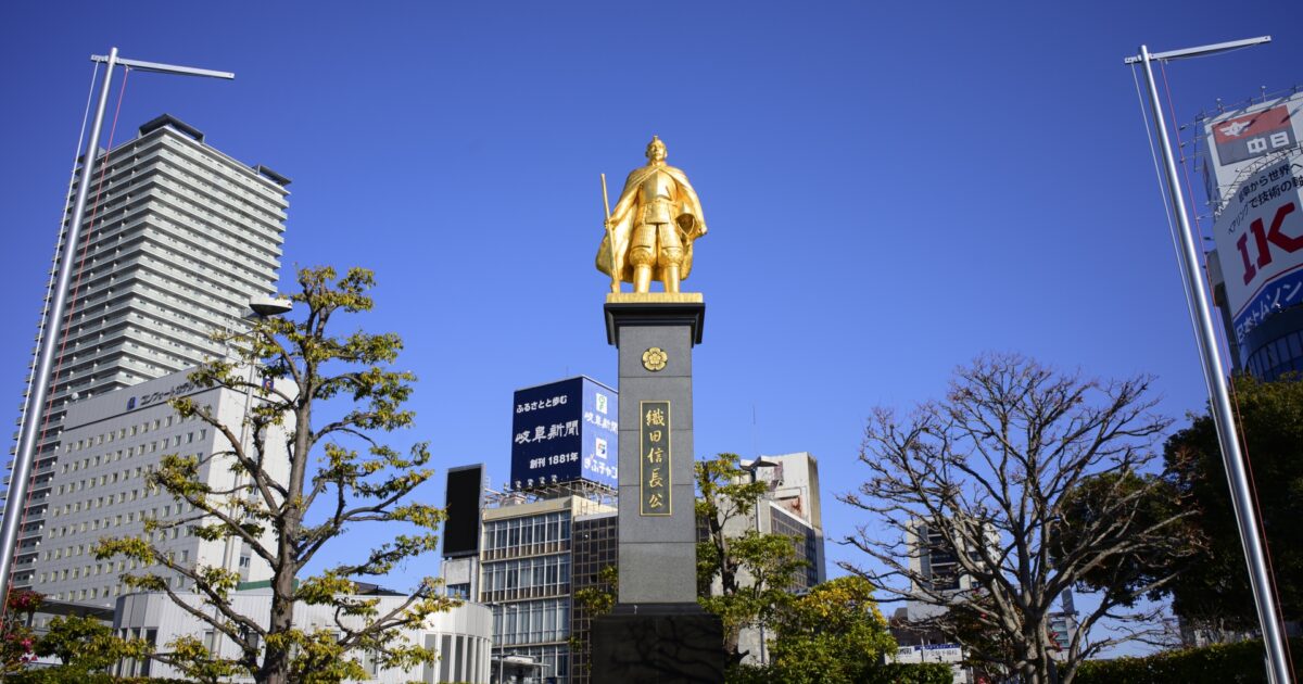 金色に輝く織田信長像と岐阜駅前のビル群
