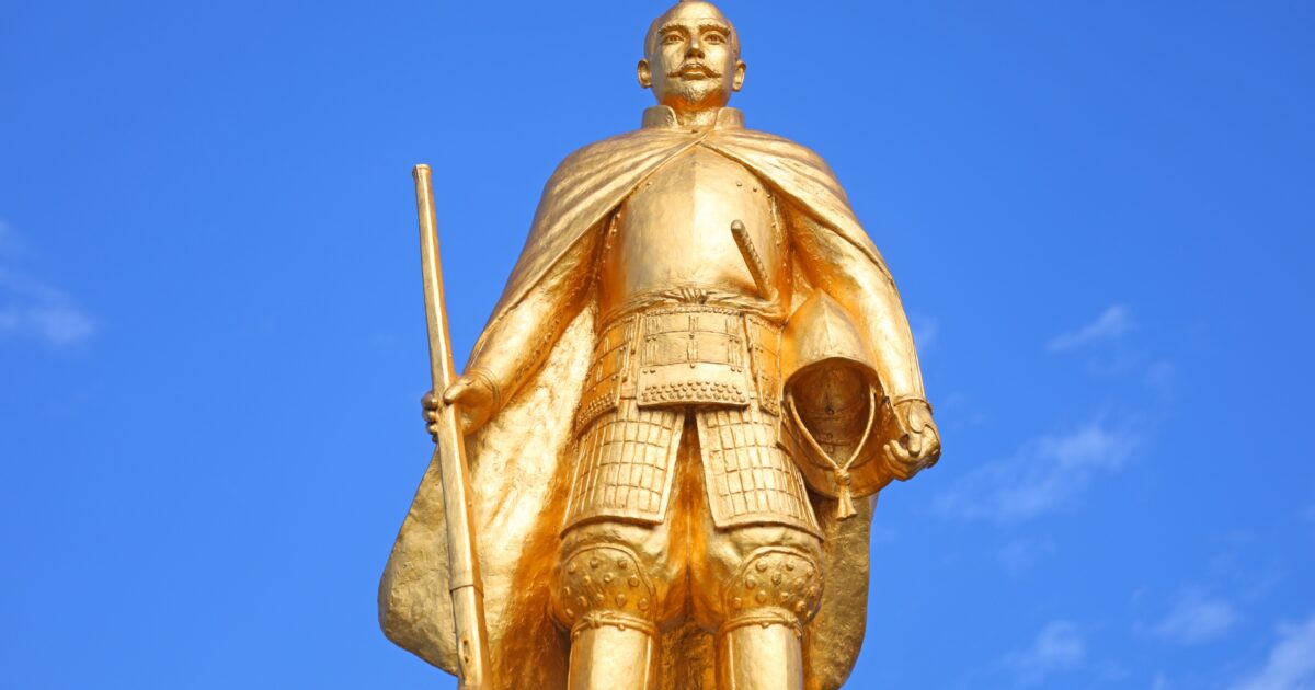 青空を背景にした金色の織田信長像のアップ