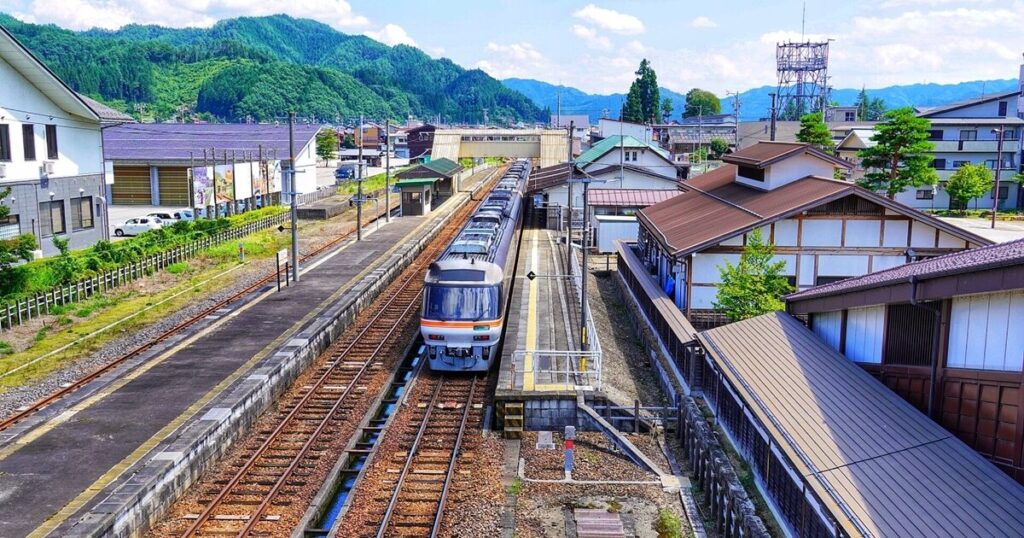 飛騨古川駅に停車する特急列車と山間の町並み