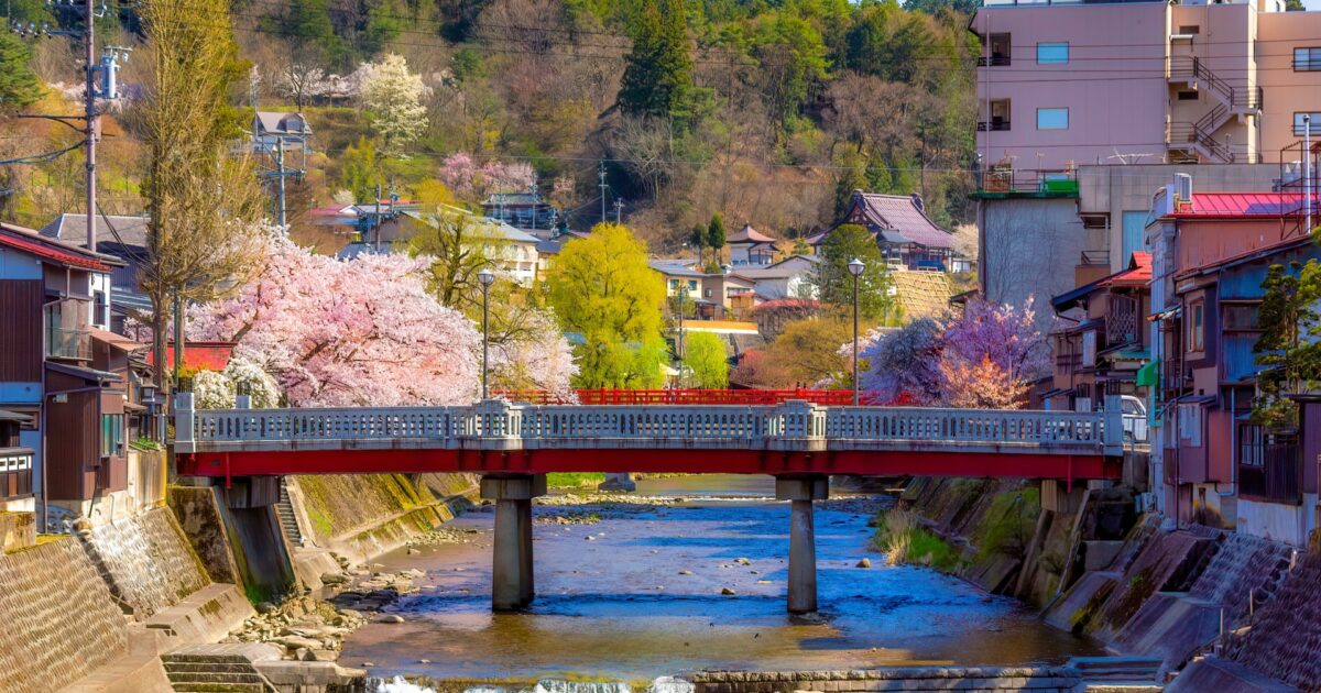 桜に囲まれた宮川沿いの橋と高山市街の春風景