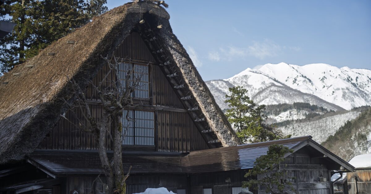 雪山を背景にした白川郷の合掌造り家屋